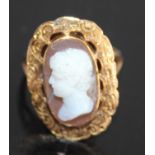 A yellow metal carved shell cameo set ring, depicting profile portrait of a young Roman male and