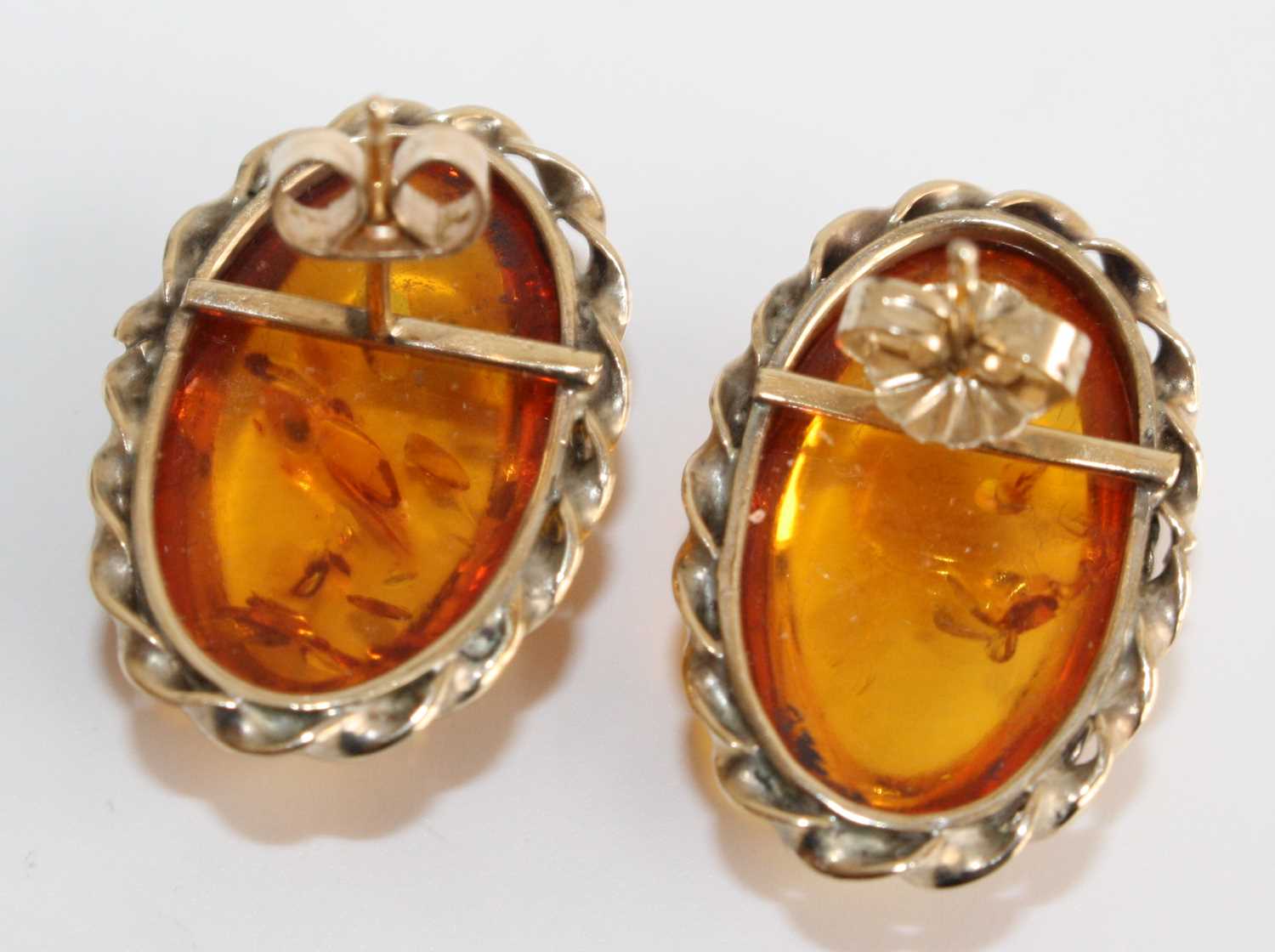 A pair of 9ct yellow gold amber stud earrings, each with an oval treated amber cabochon within a - Image 2 of 3