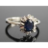A white metal, sapphire and diamond flower head cluster ring, arranged as a four-claw set oval cut