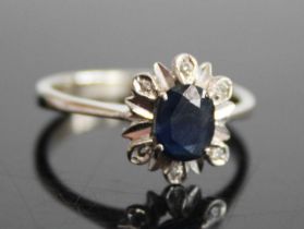 A white metal, sapphire and diamond flower head cluster ring, arranged as a four-claw set oval cut