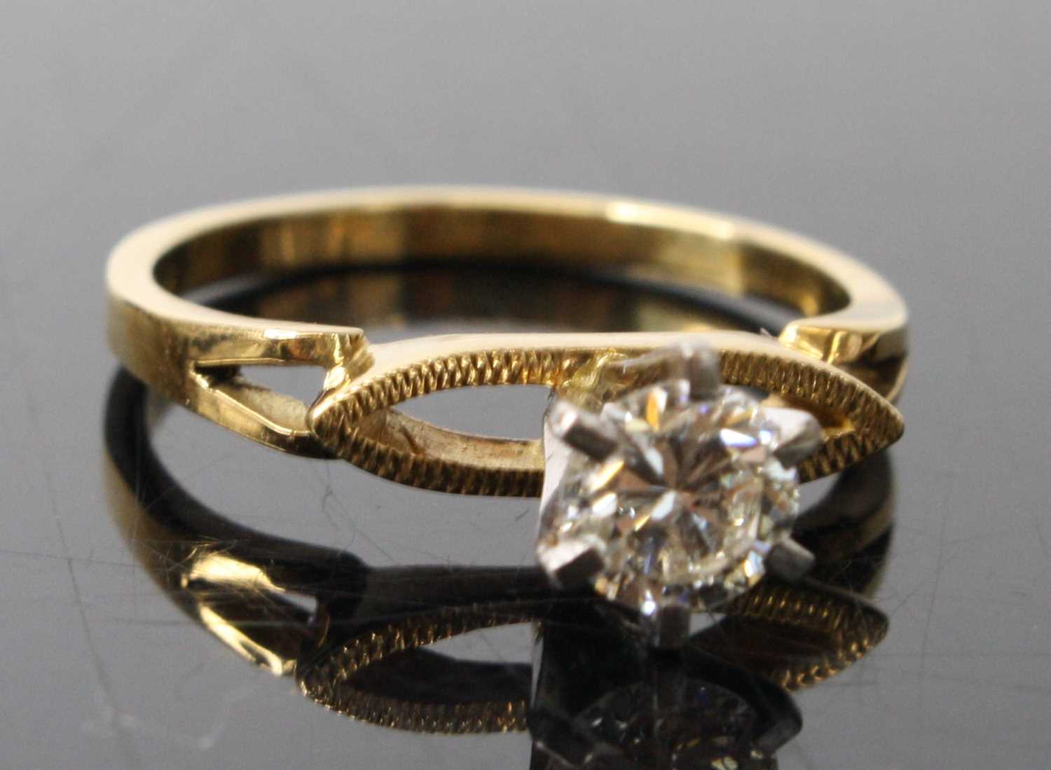 A yellow and white metal contemporary diamond solitaire ring, comprising a round brilliant cut