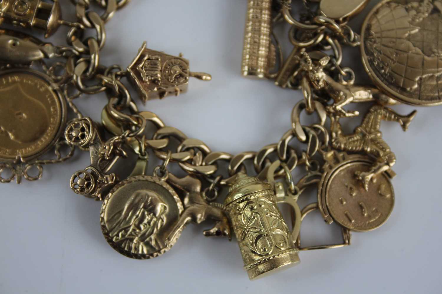 A 9ct gold curblink bracelet containing a large quantity of charms, the charms in unmarked yellow - Image 6 of 6