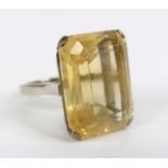 A yellow metal citrine single stone ring, featuring a rectangular cut citrine in a four-claw