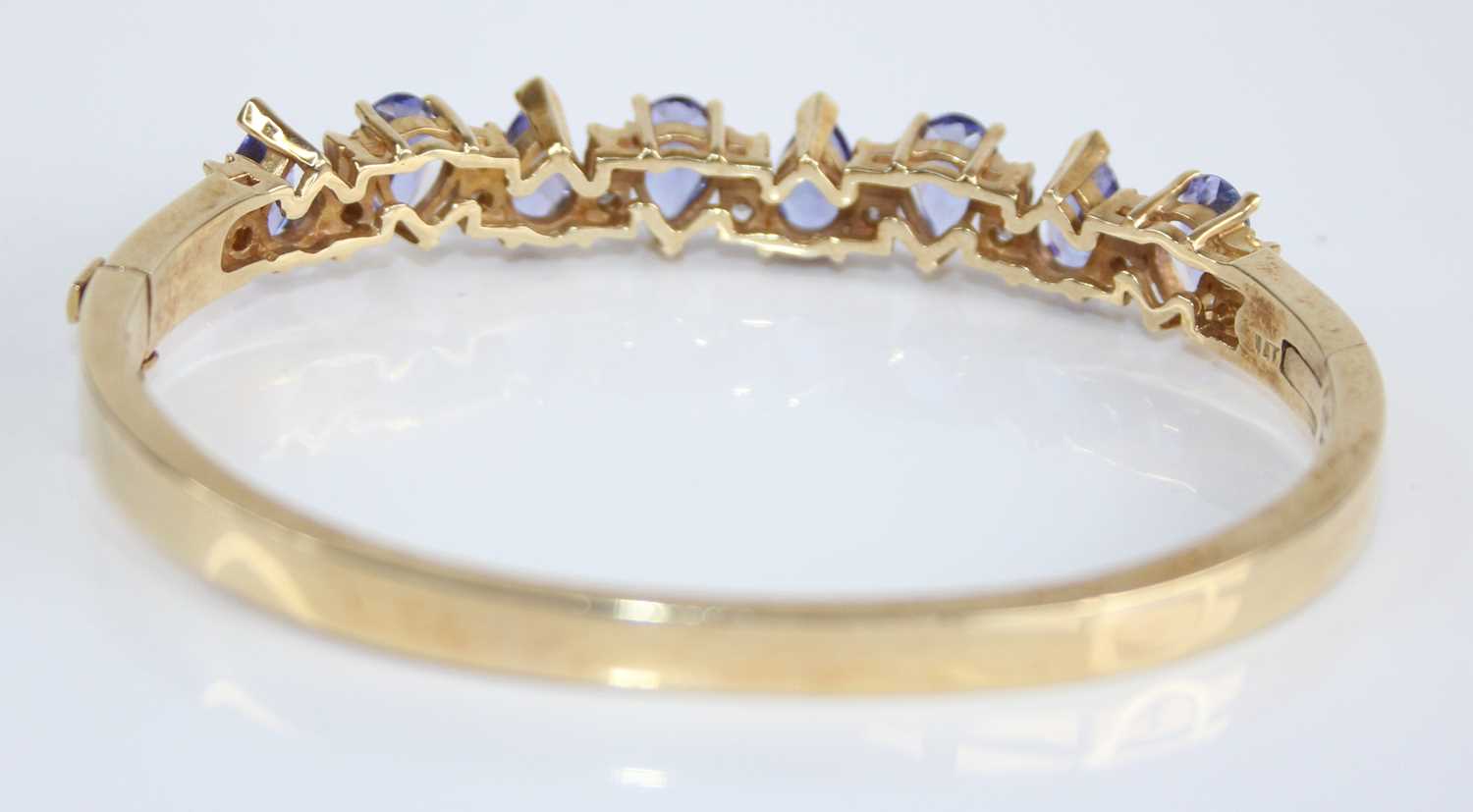 A contemporary yellow metal, tanzanite and diamond set hinged bangle, arranged as eight pear cut - Image 2 of 4