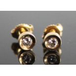 A pair of yellow metal diamond stud earrings, each featuring a round brilliant cut diamond in a