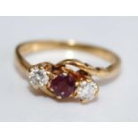 An 18ct gold, ruby and diamond three-stone crossover ring, the round cut ruby weighing approx 0.2