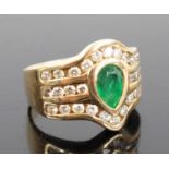 A 14ct yellow gold emerald and diamond dress ring, featuring a centre pear cut emerald in a bezel