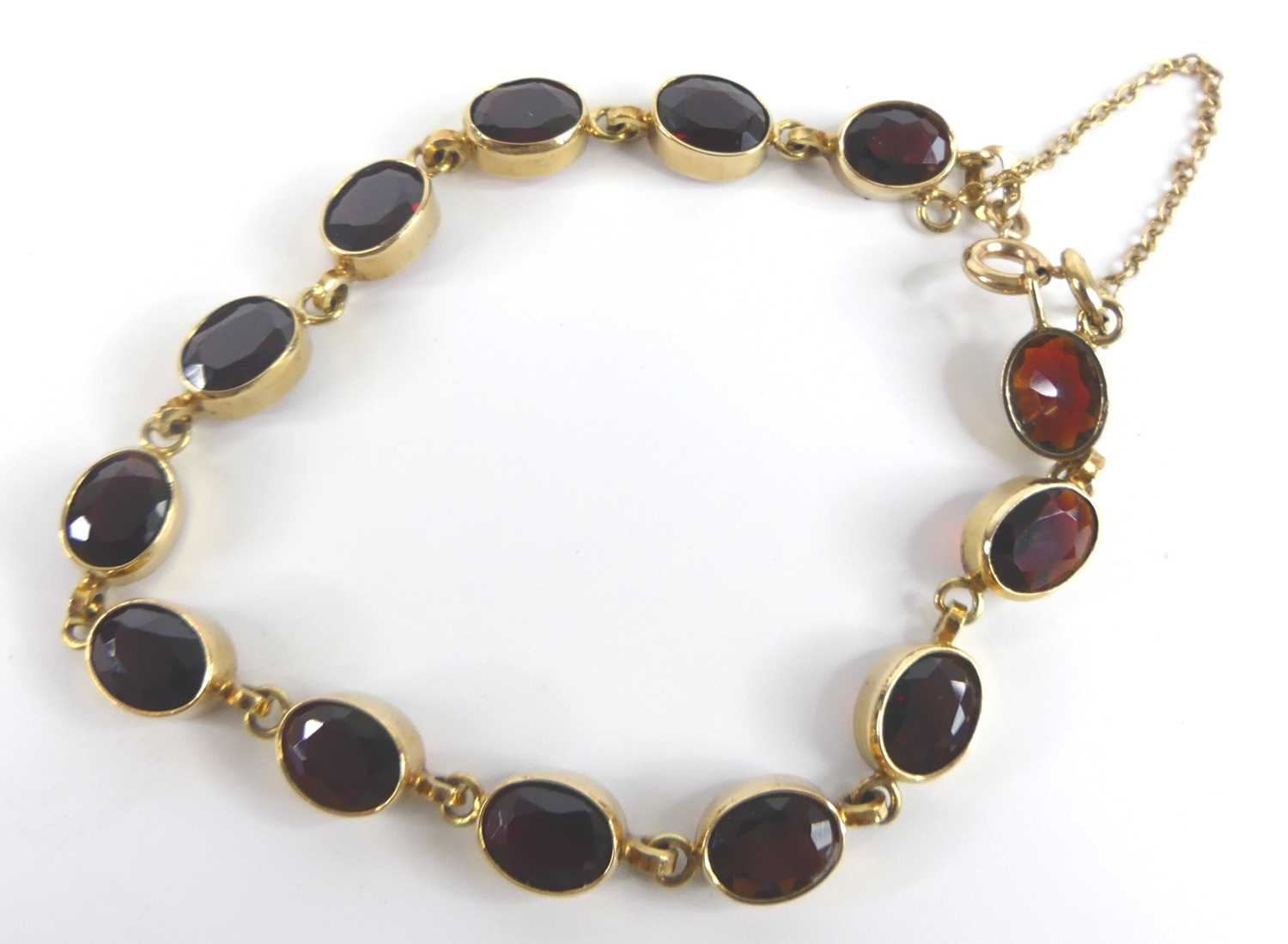 A 9ct yellow gold garnet bracelet, comprising 13 oval almandine garnets in bezel settings, with bolt - Image 2 of 4