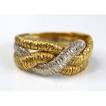 A contemporary 18ct yellow and white gold band ring, arranged as three textured interwoven bands,