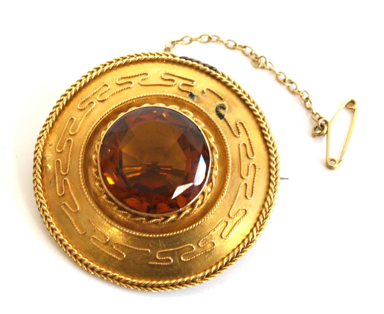 A yellow metal Etruscan style citrine target brooch featuring a central round faceted citrine within