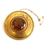 A yellow metal Etruscan style citrine target brooch featuring a central round faceted citrine within