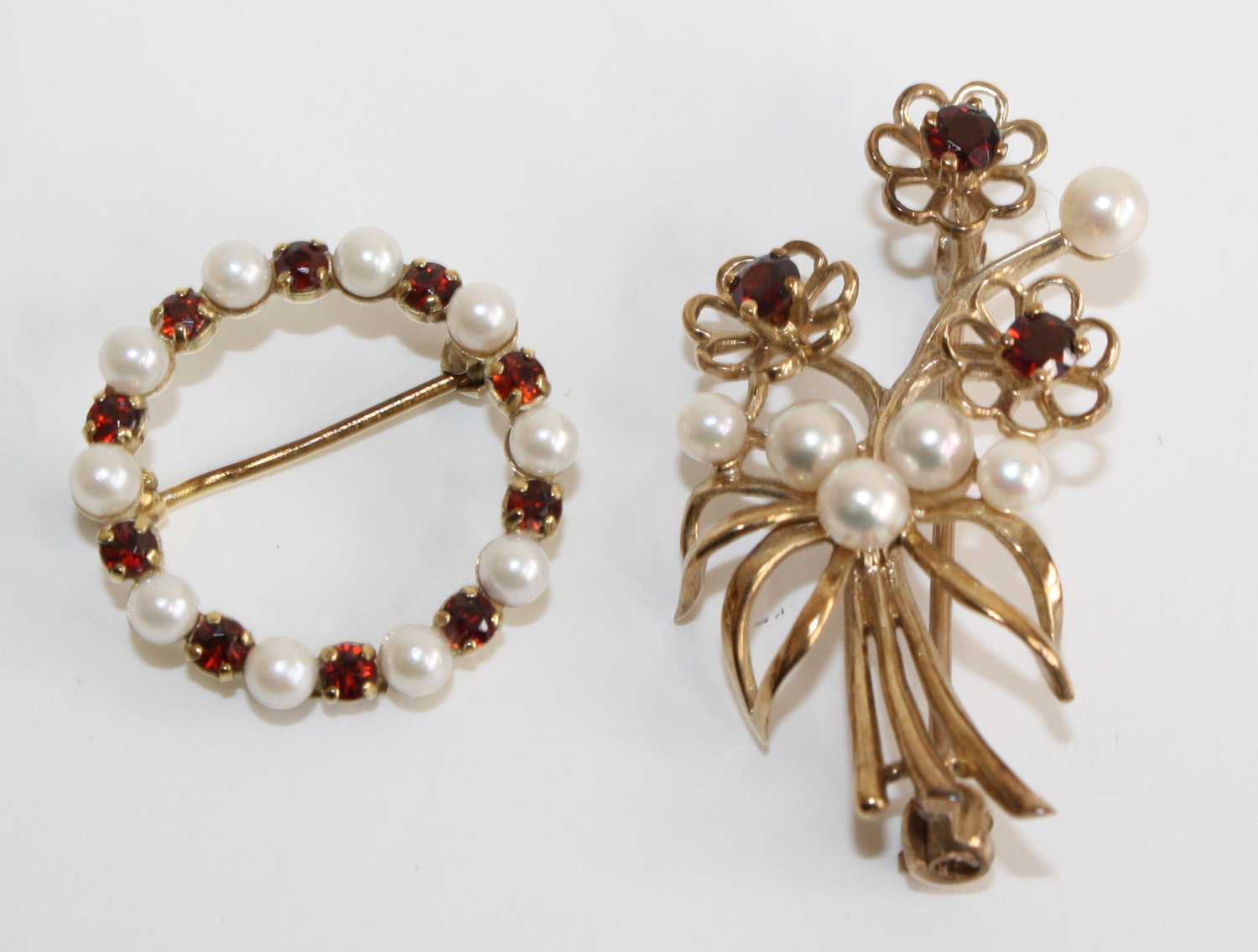 Two 9ct yellow gold, garnet and cultured pearl brooches, one designed as a floral spray with three