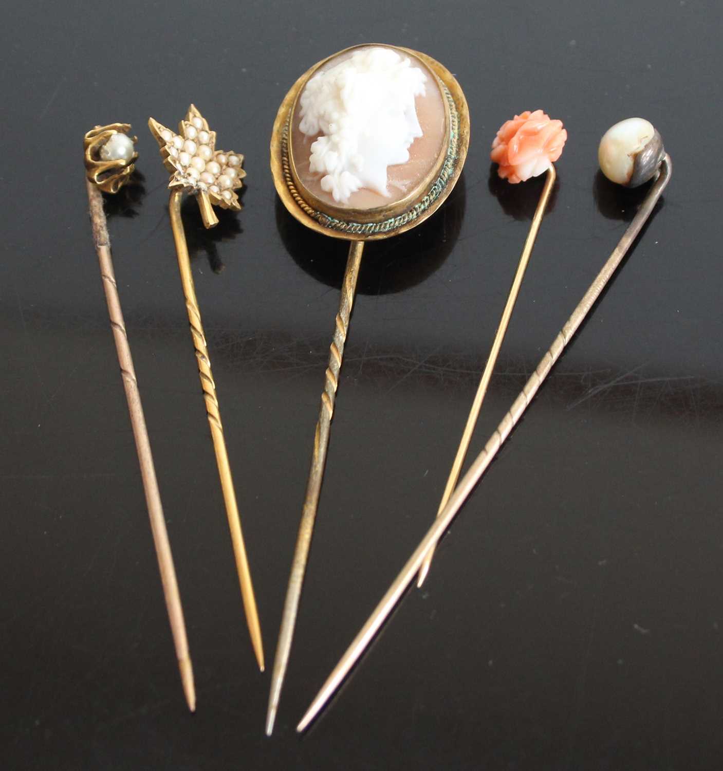 Five assorted yellow metal stick pins to include a 25mm by 20mm oval shell cameo of a classical