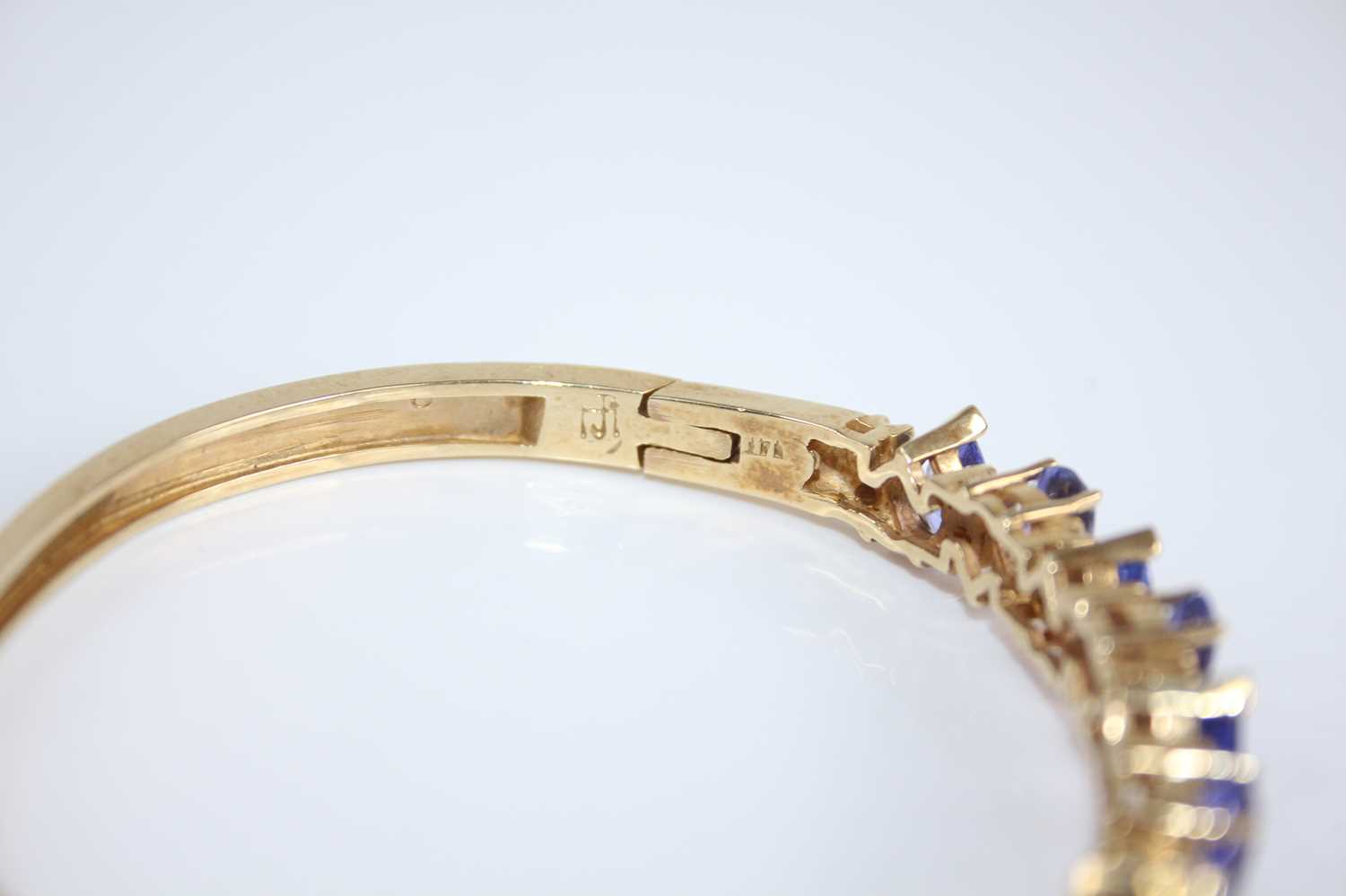 A contemporary yellow metal, tanzanite and diamond set hinged bangle, arranged as eight pear cut - Image 4 of 4