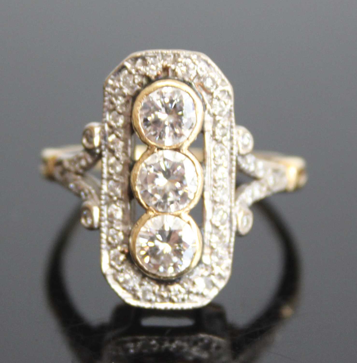 An 18ct yellow and white gold Art Deco style panel ring comprising 3 round brilliant cut diamonds in