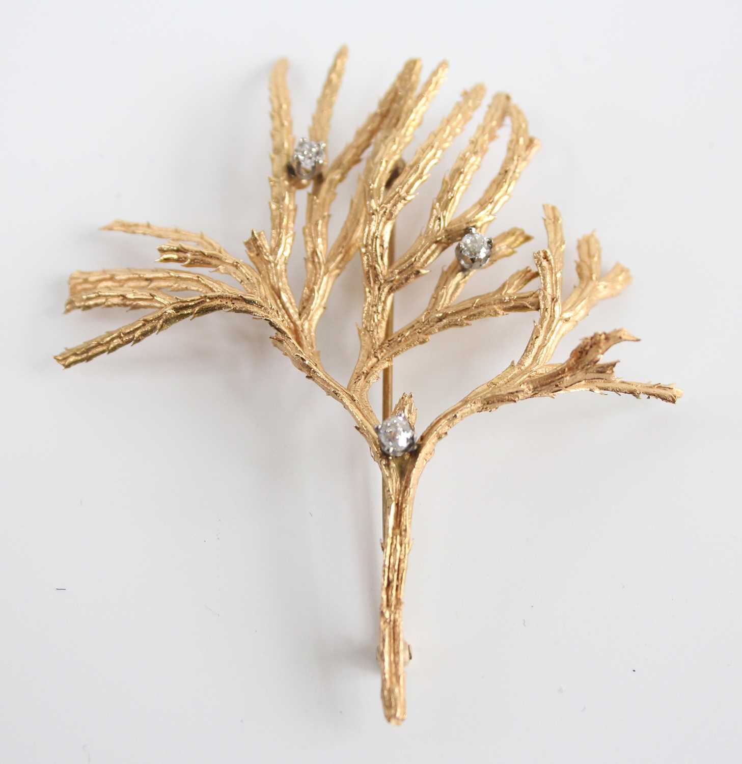 A yellow metal diamond set brooch, in the form of textured branches with three Old European cut