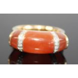 A yellow metal, carnelian and diamond dress ring, comprising two 7.4 x 4.5mm and a central 8.7 x