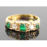 A yellow metal, emerald and diamond half eternity ring, featuring three graduated octagonal cut