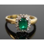 An 18ct yellow and white gold, emerald and diamond octagonal cluster ring, featuring a step cut