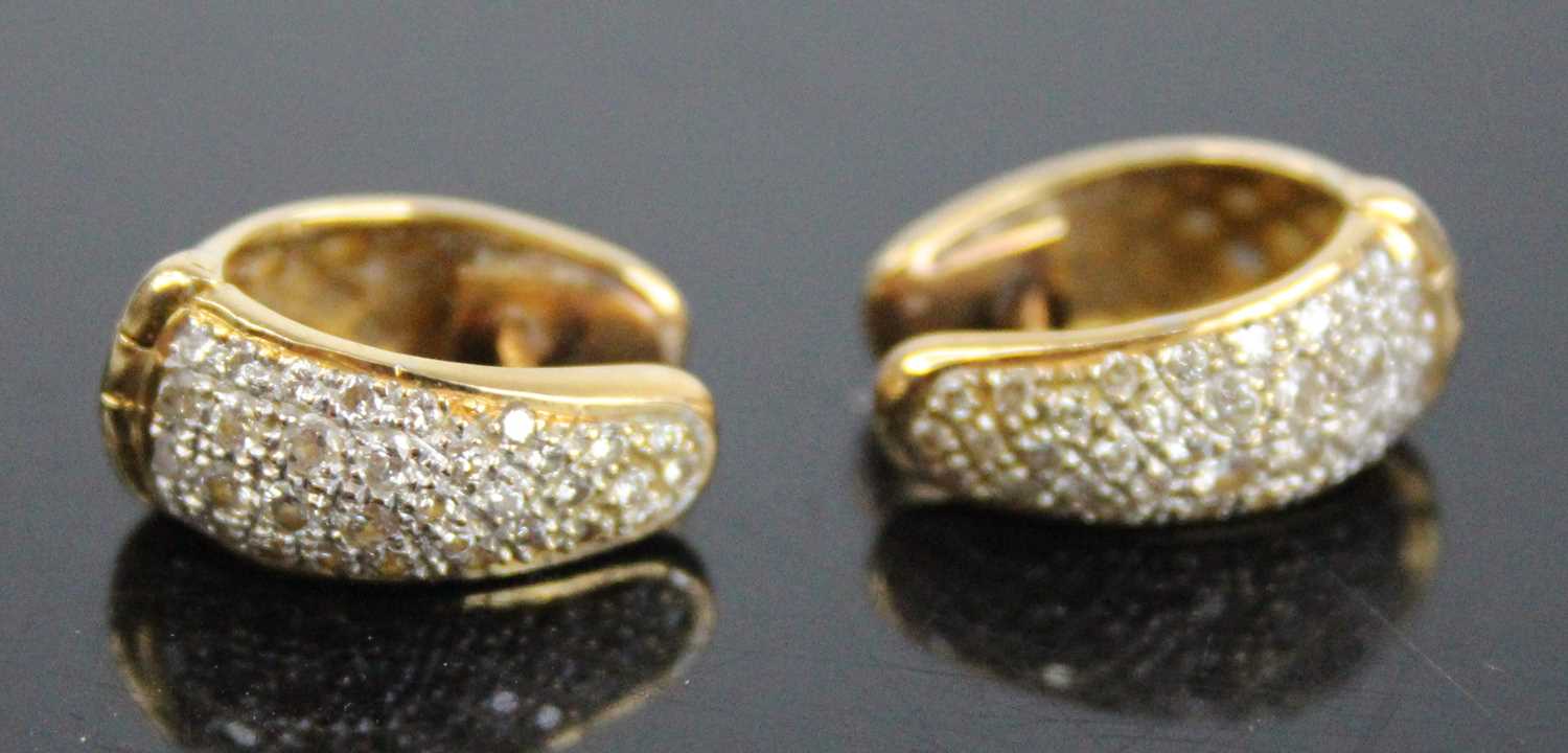 A pair of yellow metal diamond hinged huggy hoop earrings, each with 33 round brilliant cut diamonds