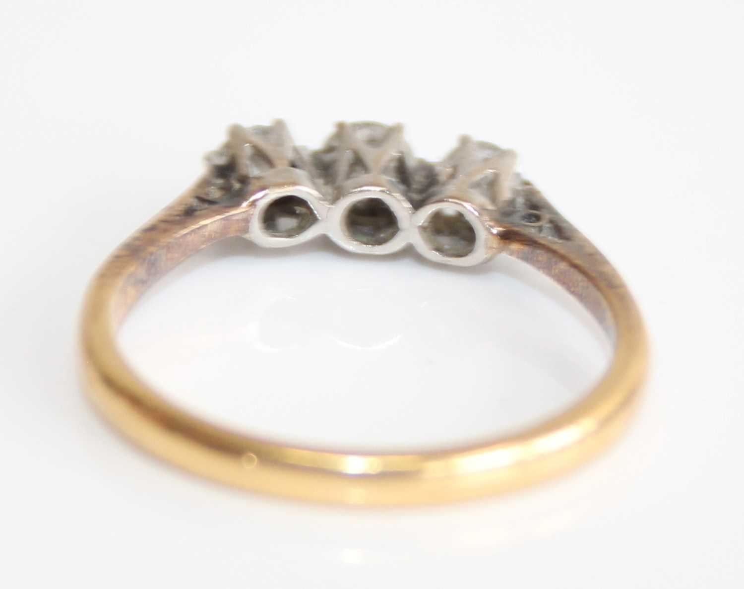An 18ct gold and platinum diamond trilogy ring, arranged as three claw set round cuts in a line - Image 3 of 6