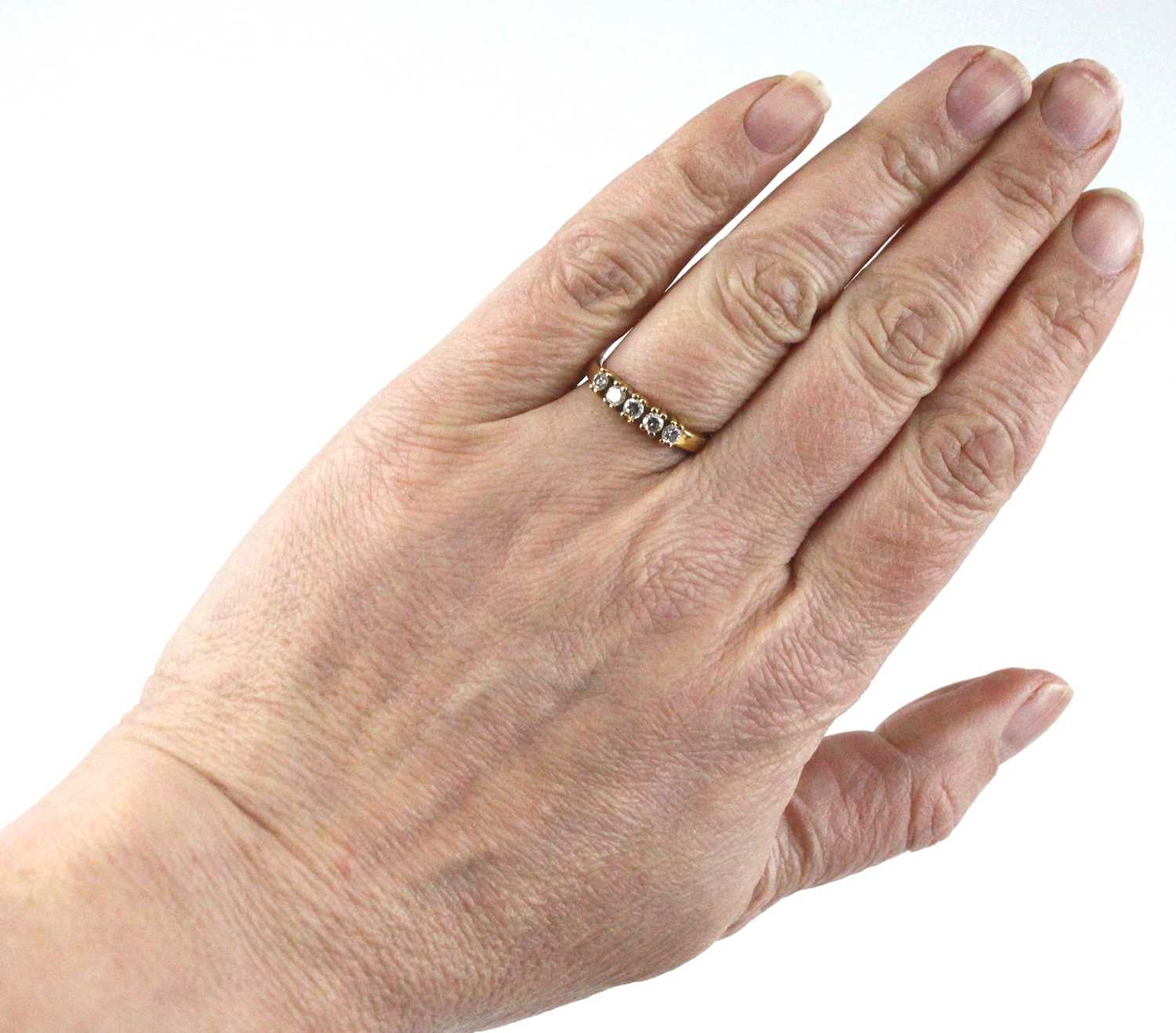 A yellow metal diamond half eternity ring, having five round brilliant cut diamonds in claw - Image 6 of 6