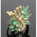 A yellow metal, emerald and diamond abstract cluster ring, featuring 16 marquise cut emeralds and 13