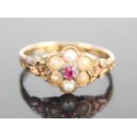 A 12ct yellow gold, ruby and pearl cluster ring, featuring a 2.5 x 2mm oval ruby and six 2.95mm half