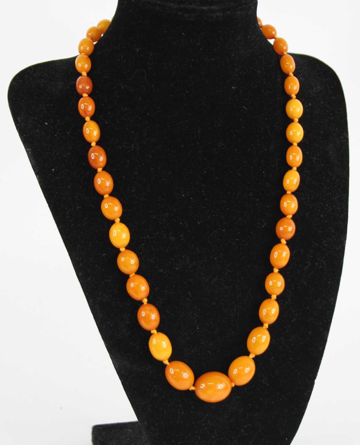 A beaded butterscotch amber single string necklace, arranged as 39 graduated barrel beads on a