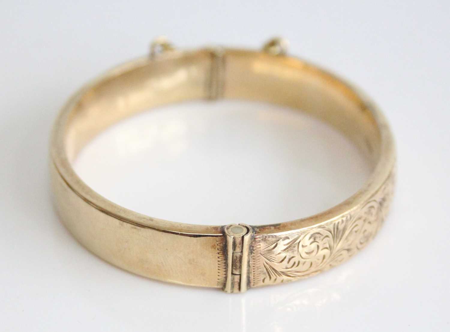 A 9ct yellow gold oval hinged hollow bangle, half engraved with scrollwork detail, with a box - Image 2 of 6