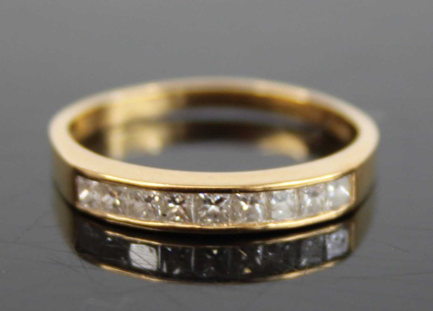 A modern 18ct gold diamond half hoop ring, arranged as seven channel set princess cuts, total
