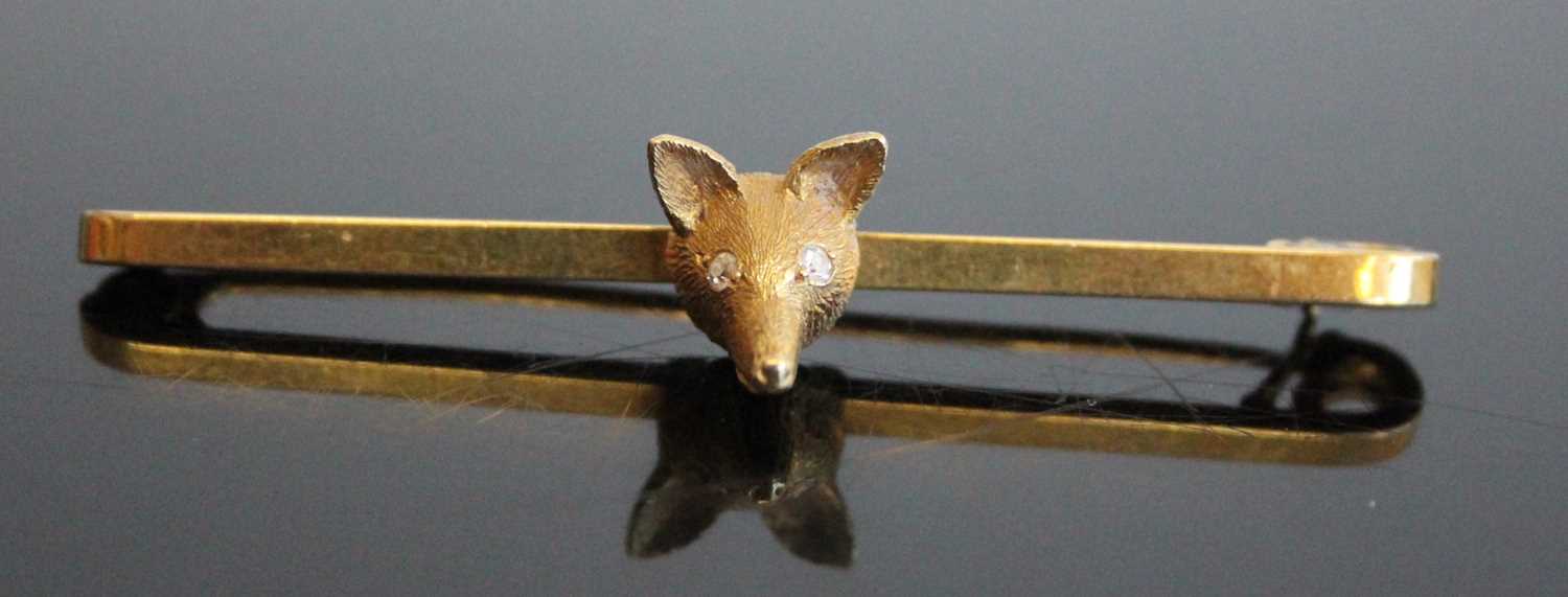 An 18ct gold safety pin bar brooch set with a fox's head, the eyes as two round cut diamonds,