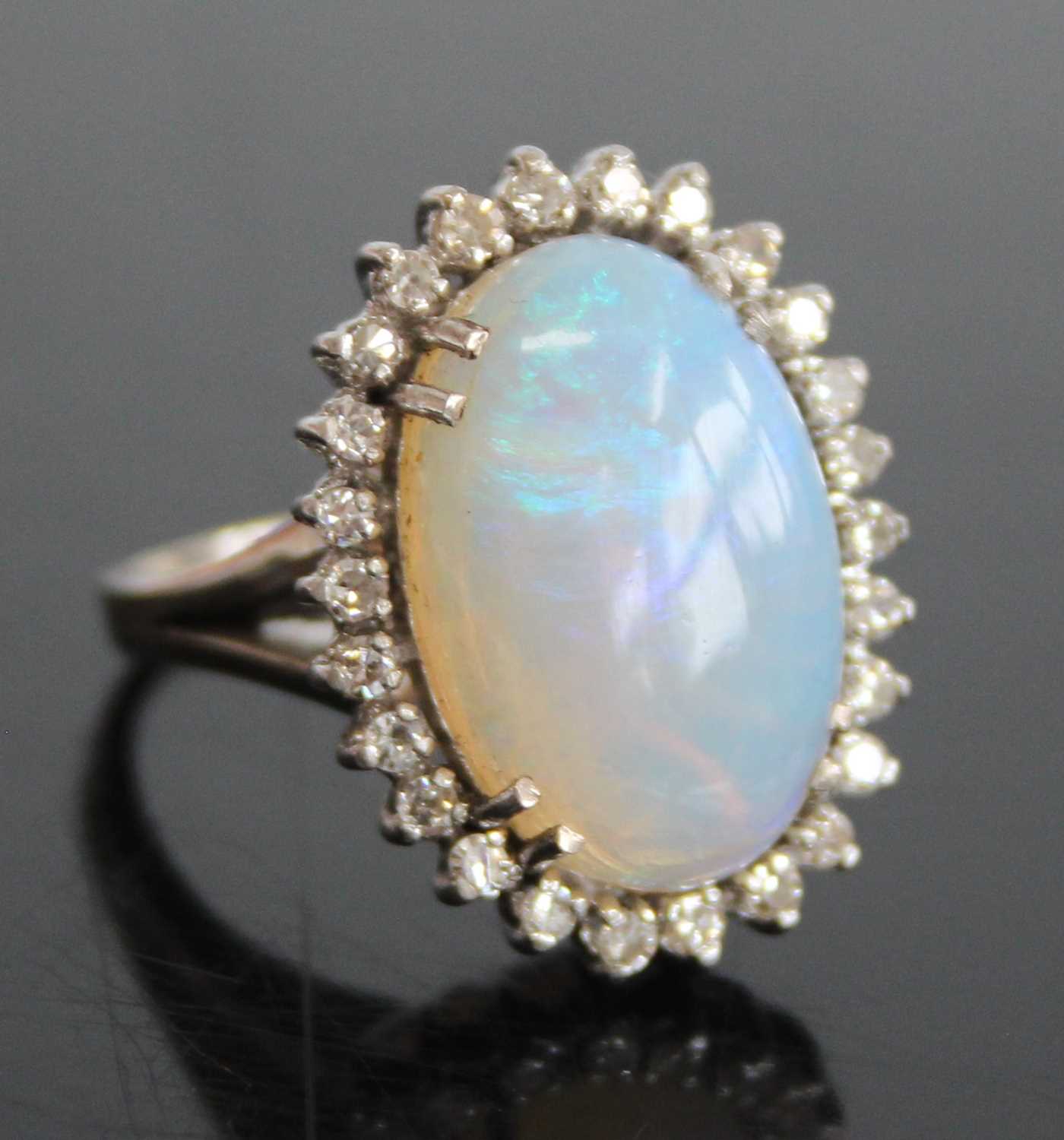 A 9ct white gold, opal and diamond oval cluster ring, comprising a central opal cabochon within a