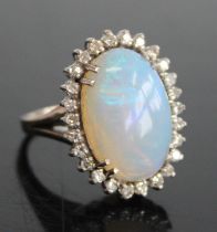 A 9ct white gold, opal and diamond oval cluster ring, comprising a central opal cabochon within a