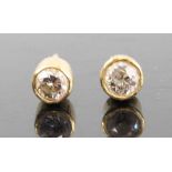 A pair of yellow metal diamond ear studs, the bezel set round cut diamonds each dia. approx 3.6mm