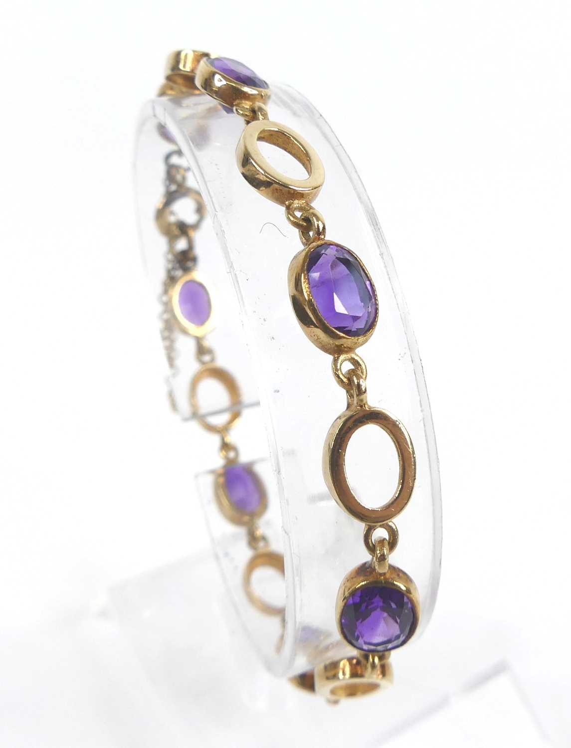 A 9ct yellow gold amethyst bracelet, featuring seven oval amethysts alternating with open oval