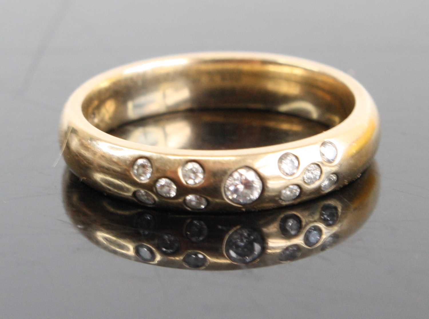 A 9ct gold diamond set band ring arranged as a centre round cut weighing approx 0.05ct, flanked to