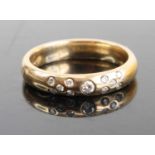 A 9ct gold diamond set band ring arranged as a centre round cut weighing approx 0.05ct, flanked to