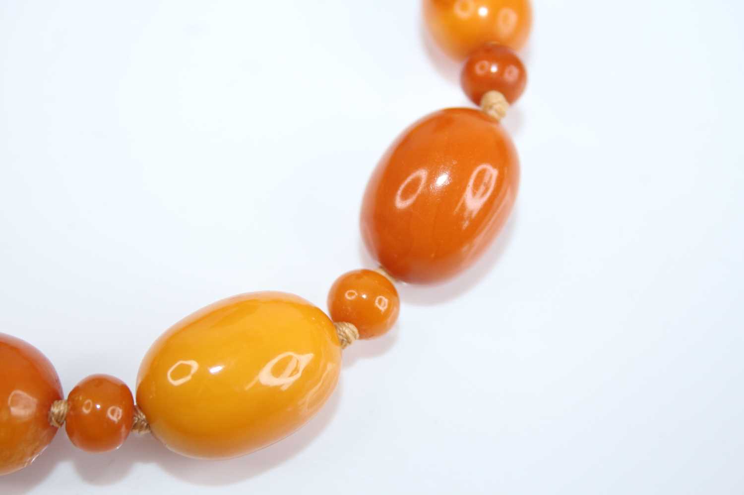 A butterscotch amber necklace, arranged as graduated barrel beads on a knotted string, each with - Image 3 of 3