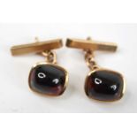 A pair of yellow metal and cabochon garnet cufflinks, 11.5 x 9.7mm, in bezel settings, unmarked