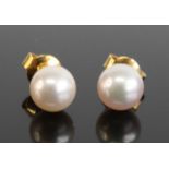 A pair of yellow metal 7.3mm cultured pearl stud earrings, having post and scroll fittings, pearls