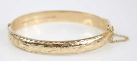 A Victorian style 9ct gold hinged bangle, having stipple engraved and carved leaf decoration,