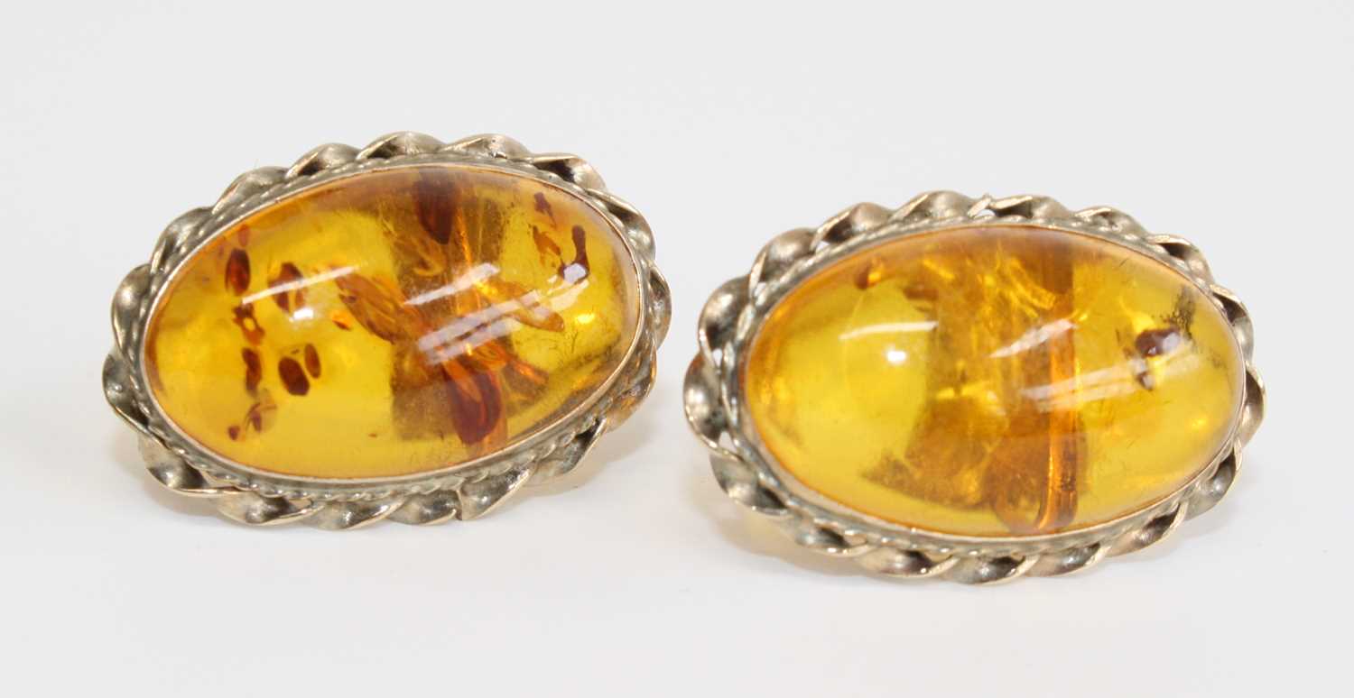 A pair of 9ct yellow gold amber stud earrings, each with an oval treated amber cabochon within a