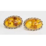 A pair of 9ct yellow gold amber stud earrings, each with an oval treated amber cabochon within a