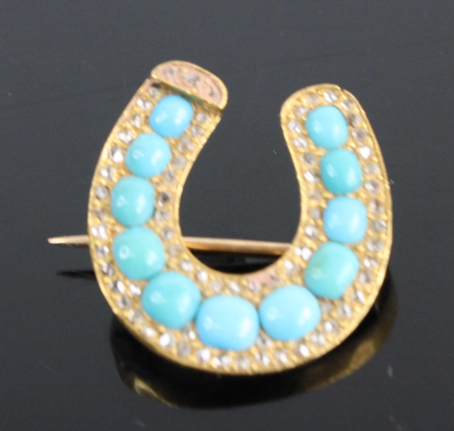 A yellow metal turquoise diamond highlight set horseshoe brooch arranged as 11 graduated turquoise