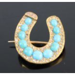 A yellow metal turquoise diamond highlight set horseshoe brooch arranged as 11 graduated turquoise