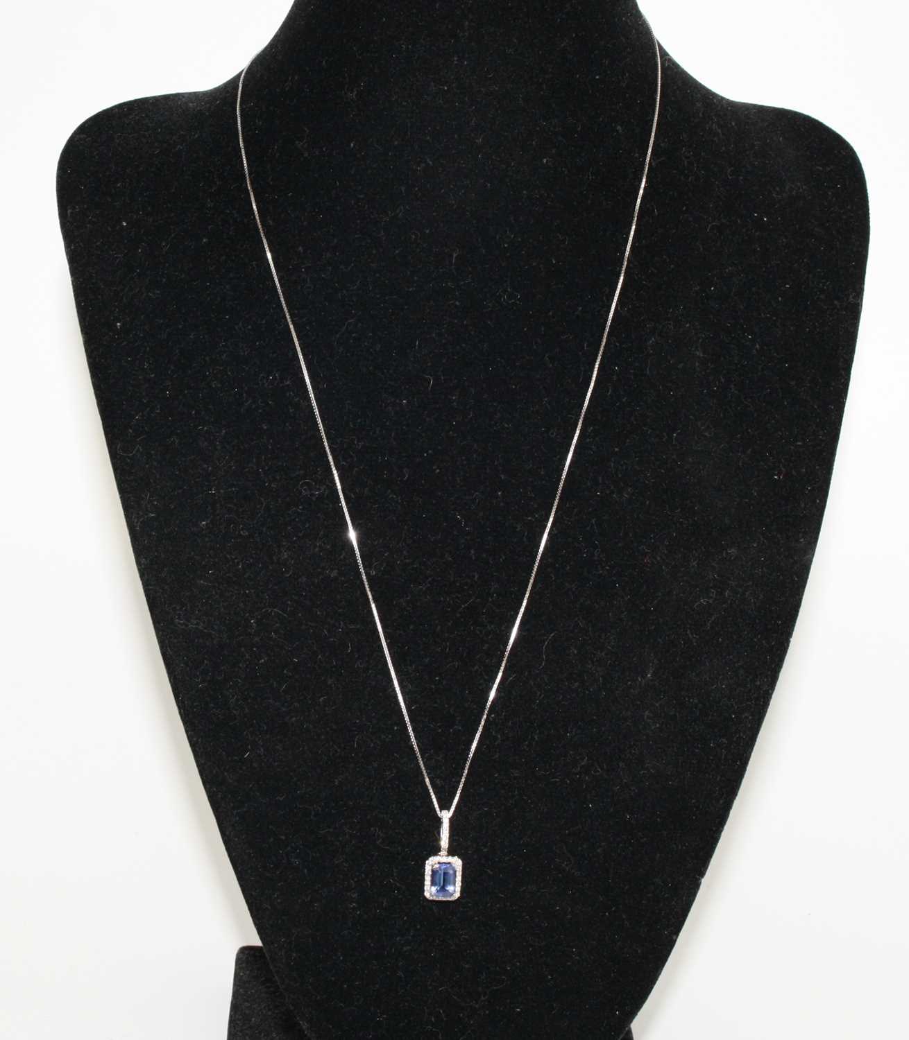 A white metal, tanzanite and diamond rectangular cluster pendant, featuring a centre step-cut