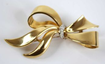 A modern 18ct gold and diamond point set ribbon brooch, being centre set with row of five small pavé