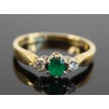 An 18ct yellow and white gold, synthetic emerald and diamond three-stone ring, the oval synthetic