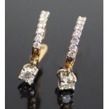 A pair of yellow and white metal diamond drop earrings, each featuring a round brilliant cut diamond